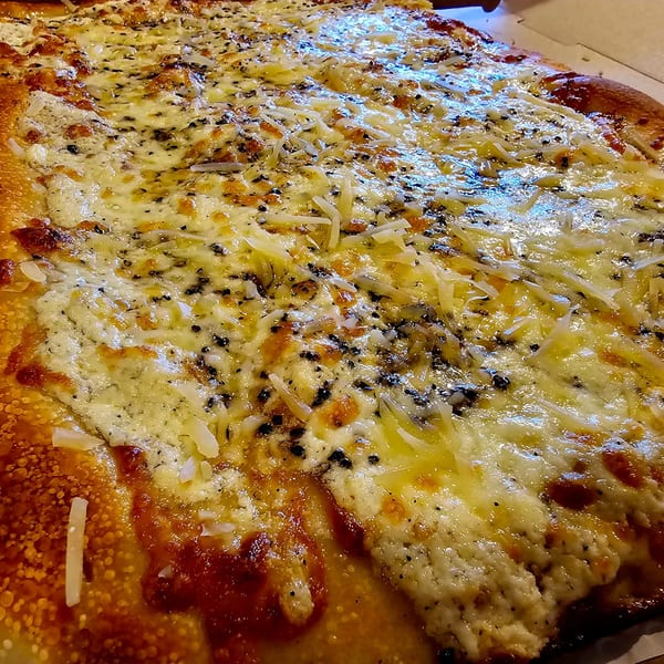 Close-up of a freshly baked Hartsdale House of Pizza white pizza with melted cheese and herbs.