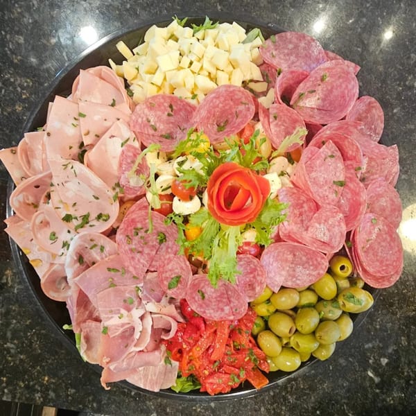 A large platter of Italian antipasto with various meats, cheeses, olives, and roasted peppers.