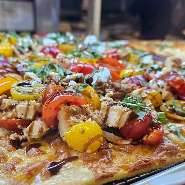 Close-up of a Hartsdale House of Pizza pie topped with chicken, tomatoes, and balsamic glaze.