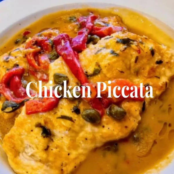 Chicken Piccata with red peppers and capers in a rich yellow sauce, served in a white bowl.