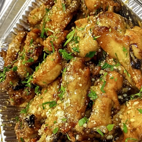 Hartsdale House of Pizza's garlic parmesan wings, glistening with sauce and topped with fresh parsley.