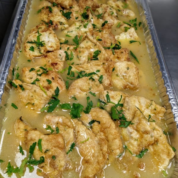Chicken Francese with parsley in a catering tray from Hartsdale House of Pizza.