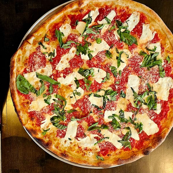 A large, round pizza from Hartsdale House of Pizza with red sauce, white cheese, and fresh basil.