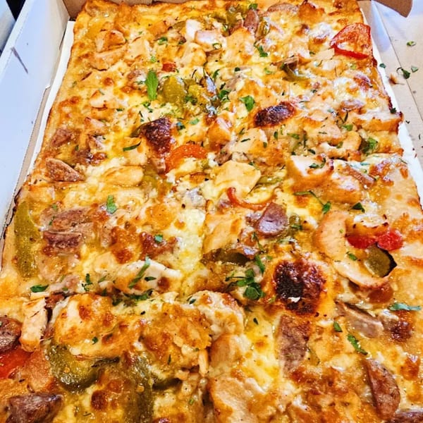 A rectangular Hartsdale House of Pizza pie with chicken, peppers, and melted cheese in a box.