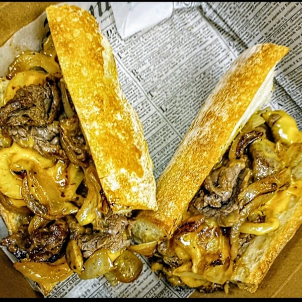 A hearty cheesesteak sandwich with steak, melted cheese, and caramelized onions on a toasted baguette.