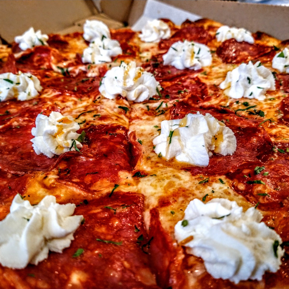 Close-up of a pepperoni pizza from Hartsdale House of Pizza, topped with dollops of ricotta cheese and herbs.
