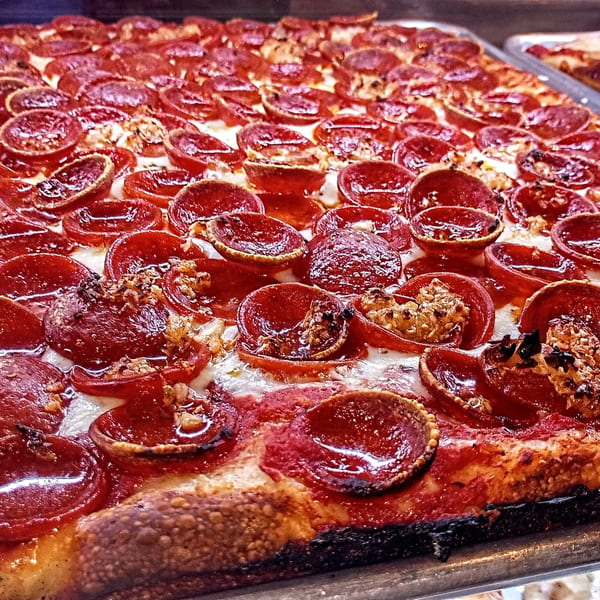Close-up of a large rectangular pepperoni pizza with crispy edges and melted cheese.