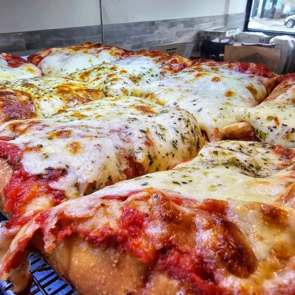 Close-up of a freshly baked Hartsdale House of Pizza cheese pizza with visible herbs and tomato sauce.